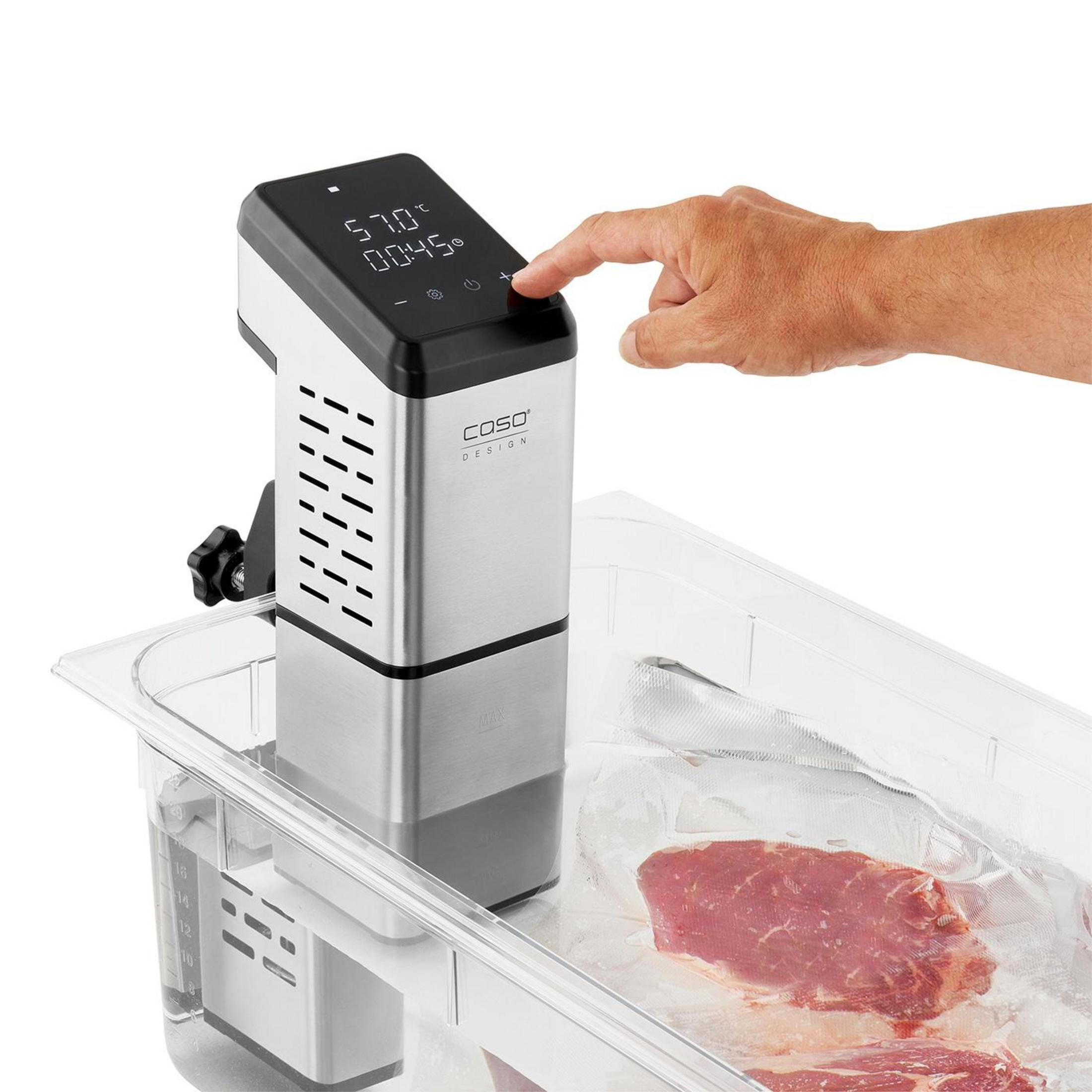 Un uomo aziona una macchina per sous vide con carne in un bagno d'acqua.