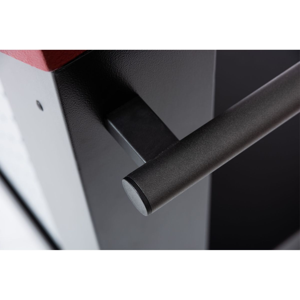 Nahaufnahme eines schwarzen Metallgriffs an einer schwarzen Oberfläche mit rotem Akzent.