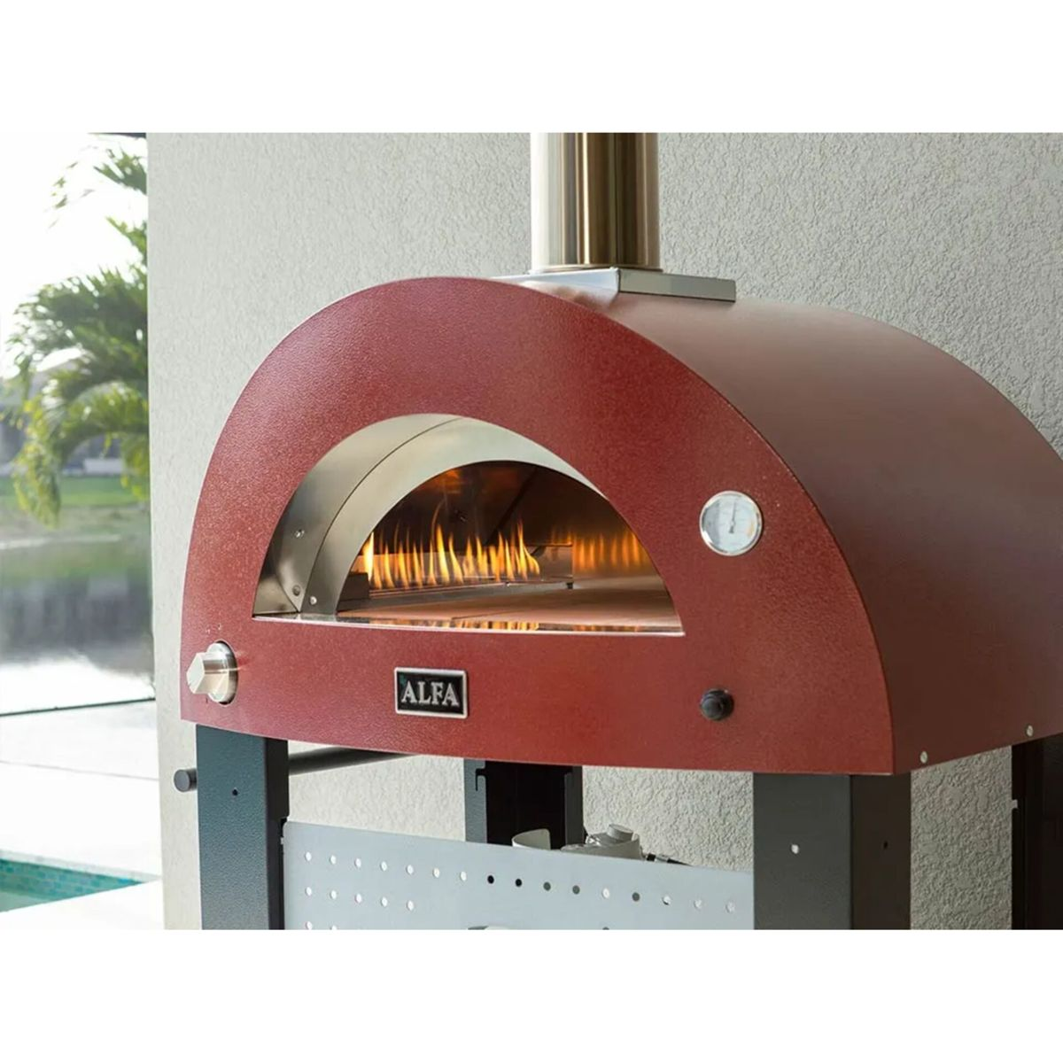 Ein roter Pizzaofen mit brennenden Flammen im Inneren steht im Freien.