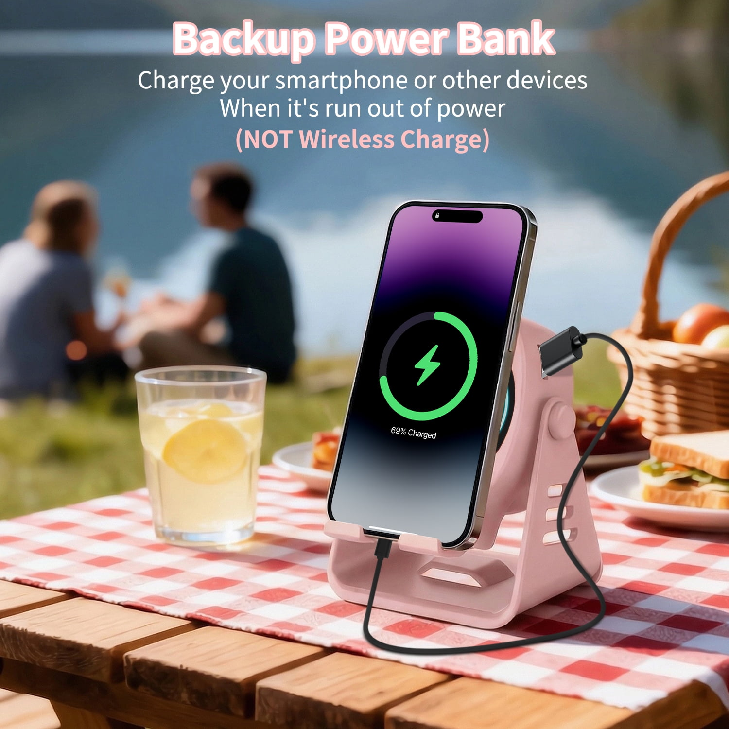 Ein rosafarbenes Powerbank-Ladegerät mit einem iPhone, das auf einem Picknicktisch aufgeladen wird.