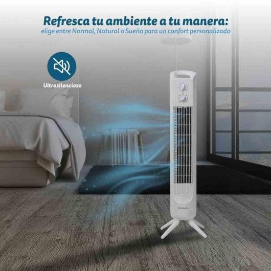 Un ventilador de torre blanco está en un dormitorio, soplando aire fresco.