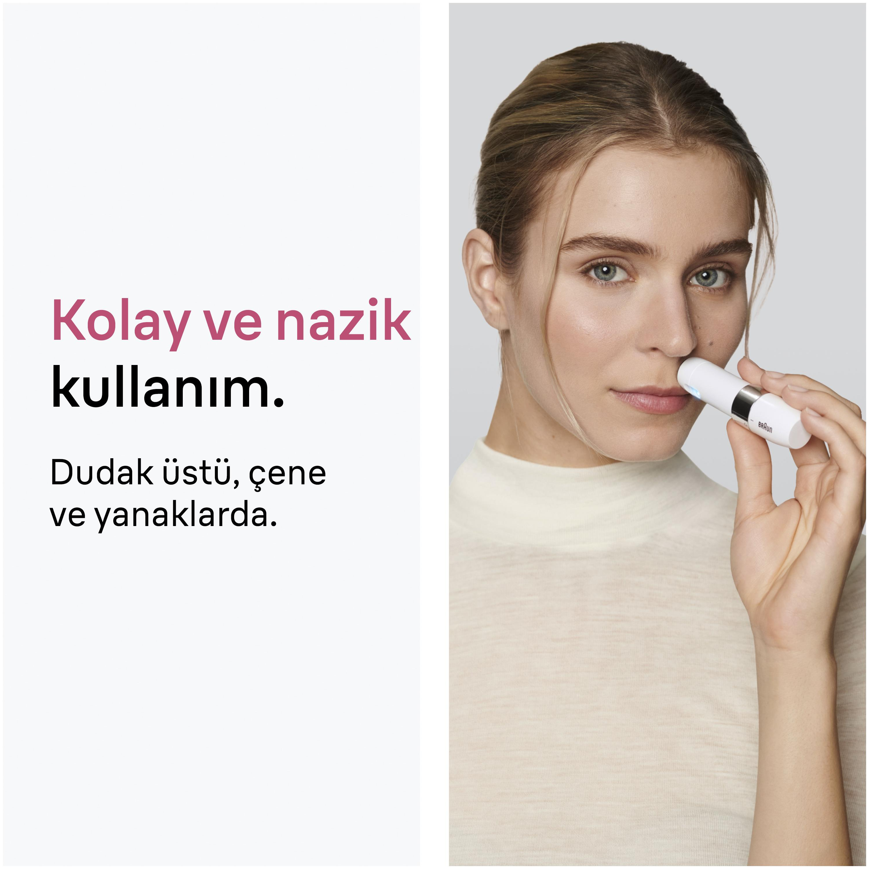 Kadın burnunda beyaz bir cilt bakım cihazı kullanıyor.