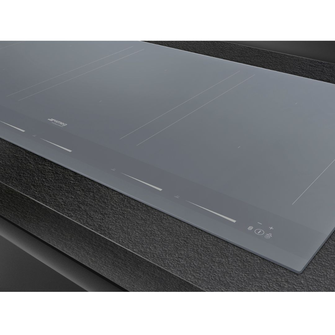 Piano cottura a induzione grigio con marcature zone e pulsanti.