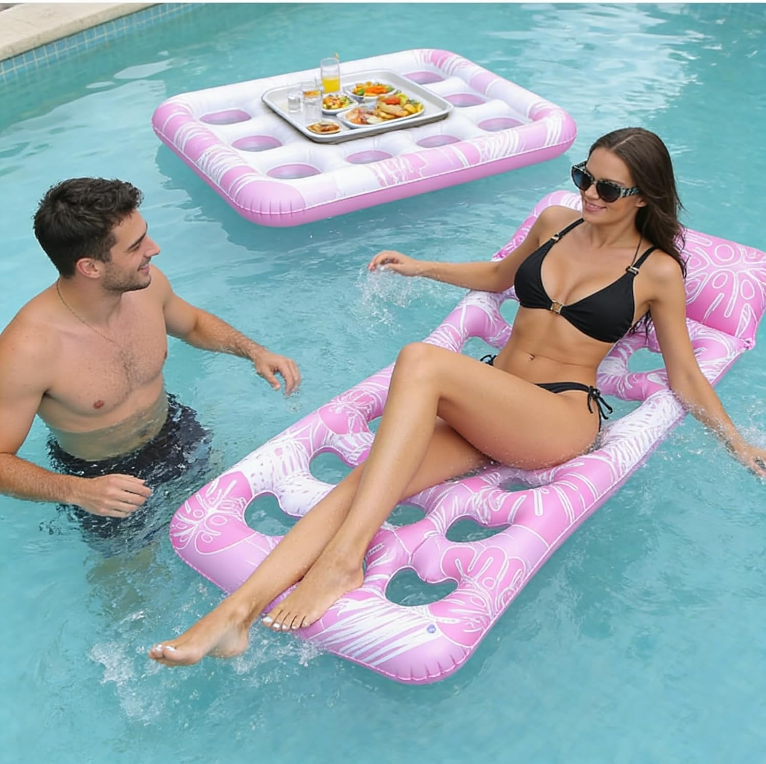 Ein Mann und eine Frau entspannen sich auf aufblasbaren Schwimminseln in einem Pool mit Essen und Getränken.