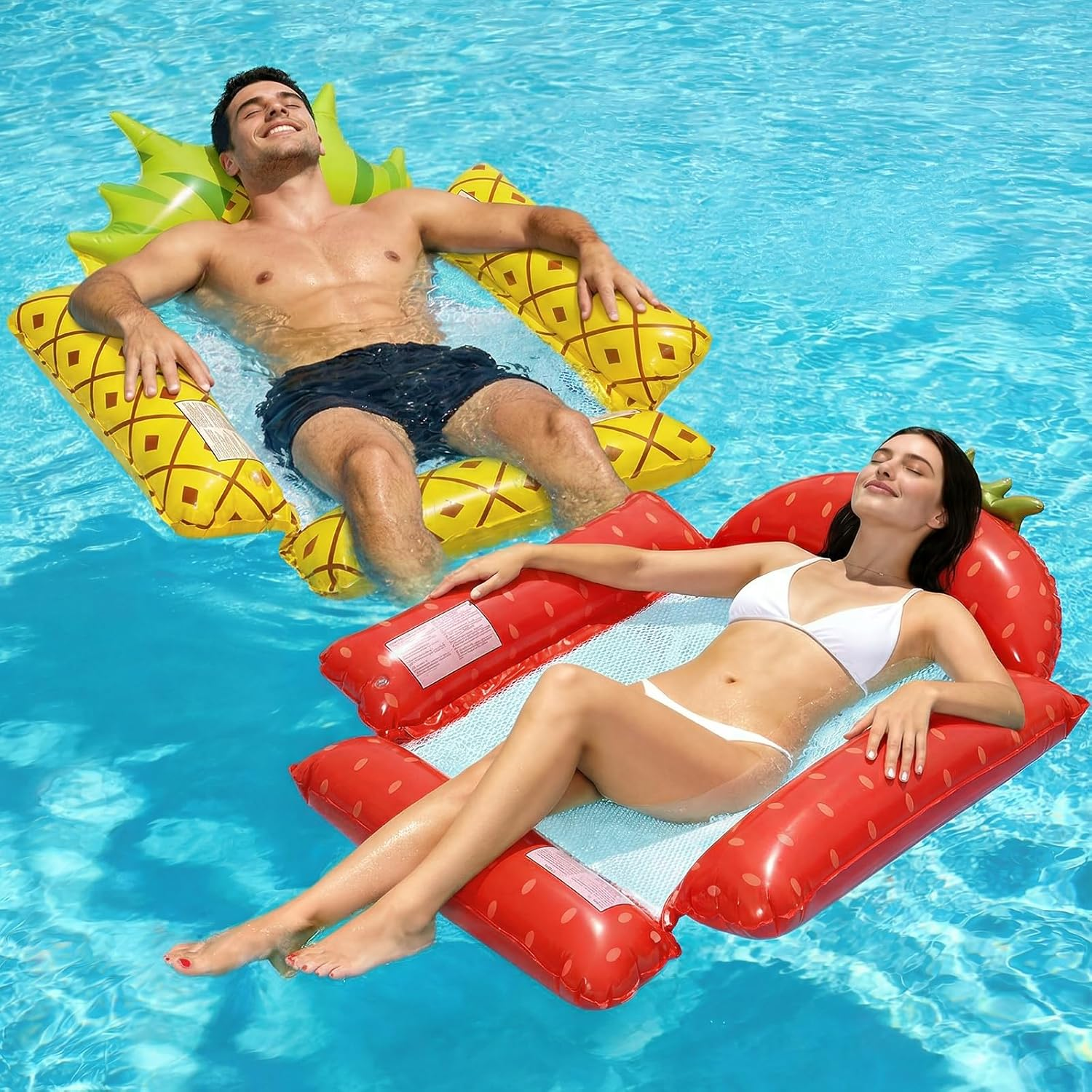 Paar entspannt auf aufblasbaren Poolschwimmern: Mann auf Ananas, Frau auf Erdbeere.