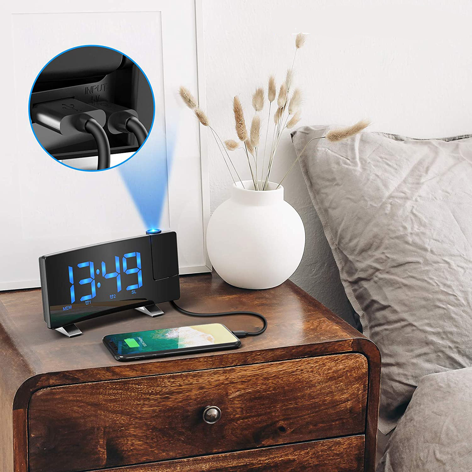 Ein Digitalwecker projiziert die Uhrzeit 13:49 an eine Wand und lädt ein Handy.