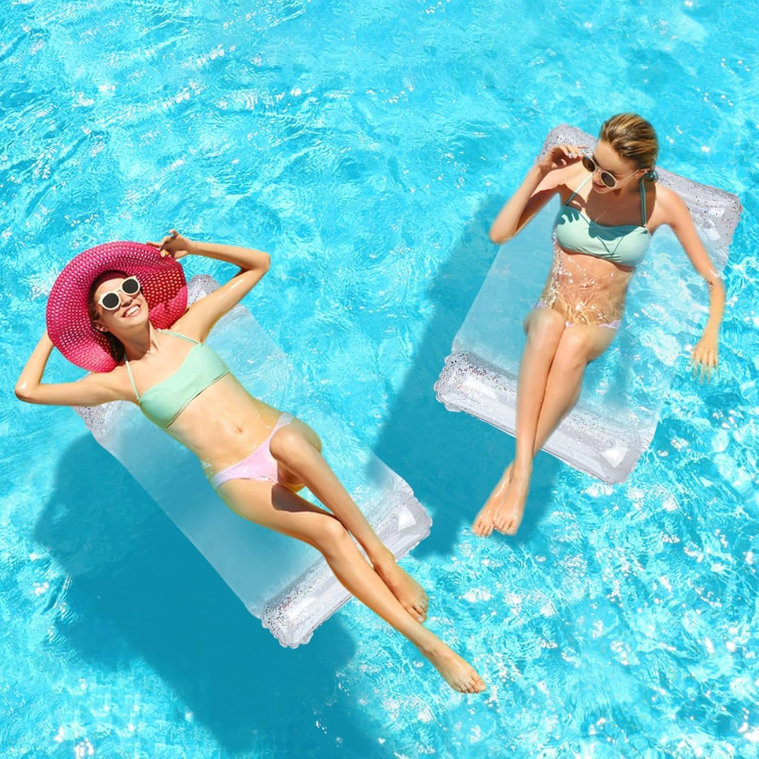 Zwei Frauen in Bikinis entspannen auf aufblasbaren Flößen in einem hellblauen Pool.