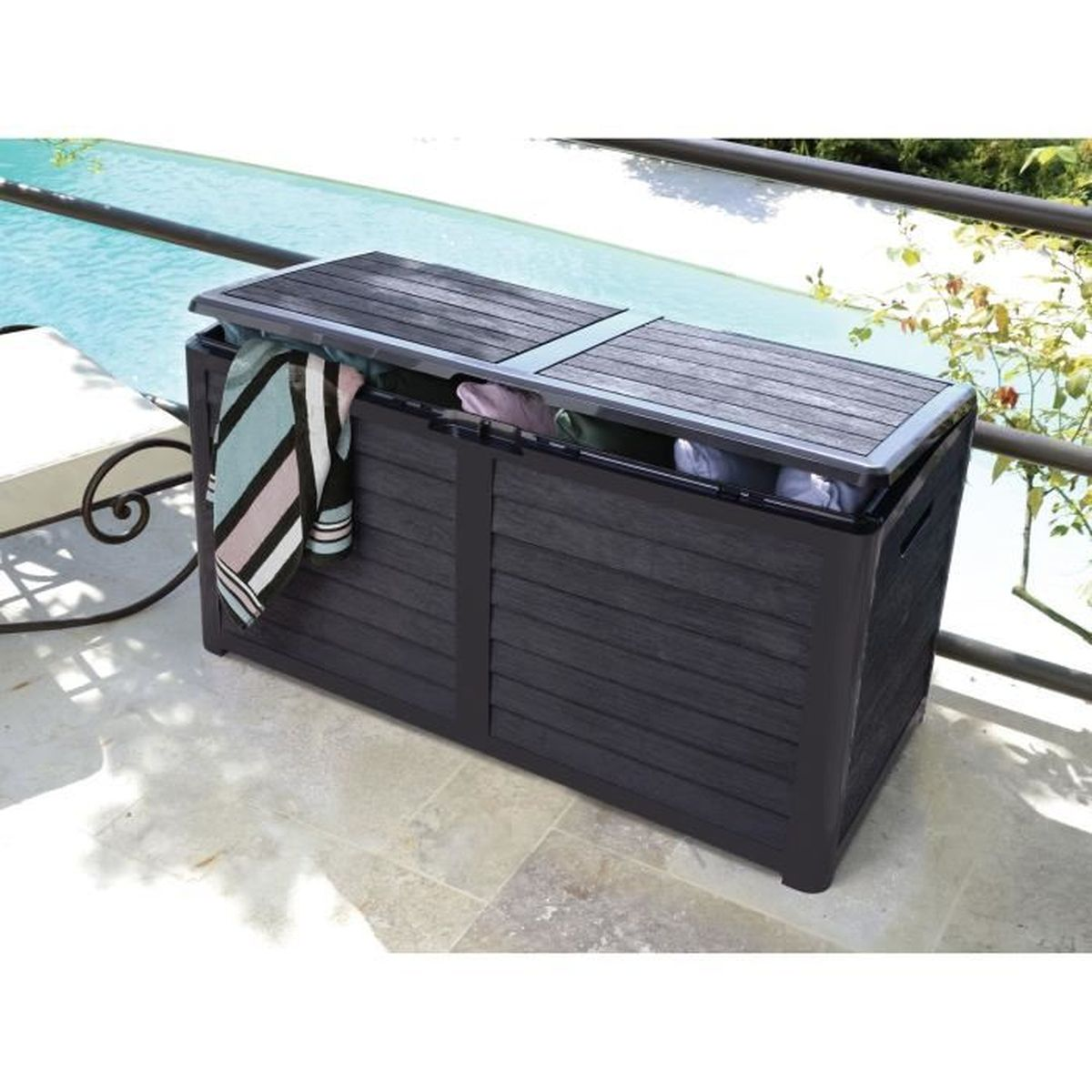Eine dunkle Aufbewahrungsbox mit offenem Deckel steht auf einer Terrasse neben einem Pool.