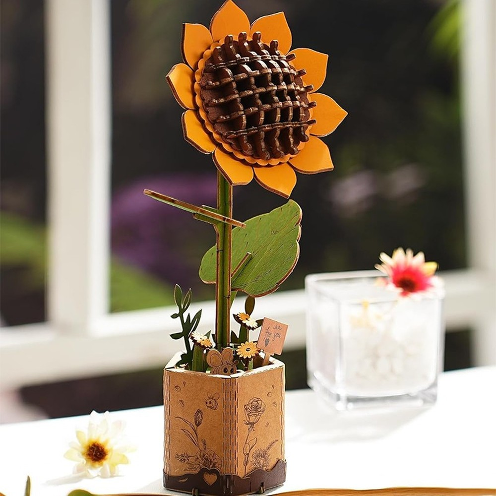 Un modèle de tournesol en bois dans un pot orné sur une table.