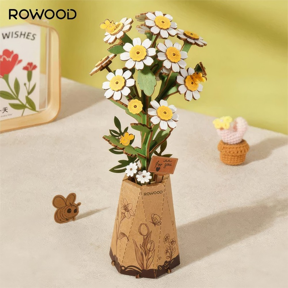 Un modello di fiore in legno con margherite bianche e accenti gialli in un vaso marrone.