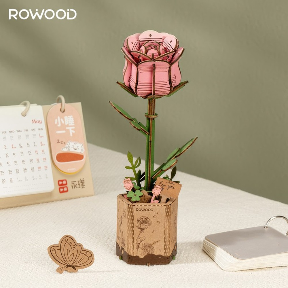 Ein rosa Holzrosen-Bausatz in einem Topf mit Schmetterling und Kalender.
