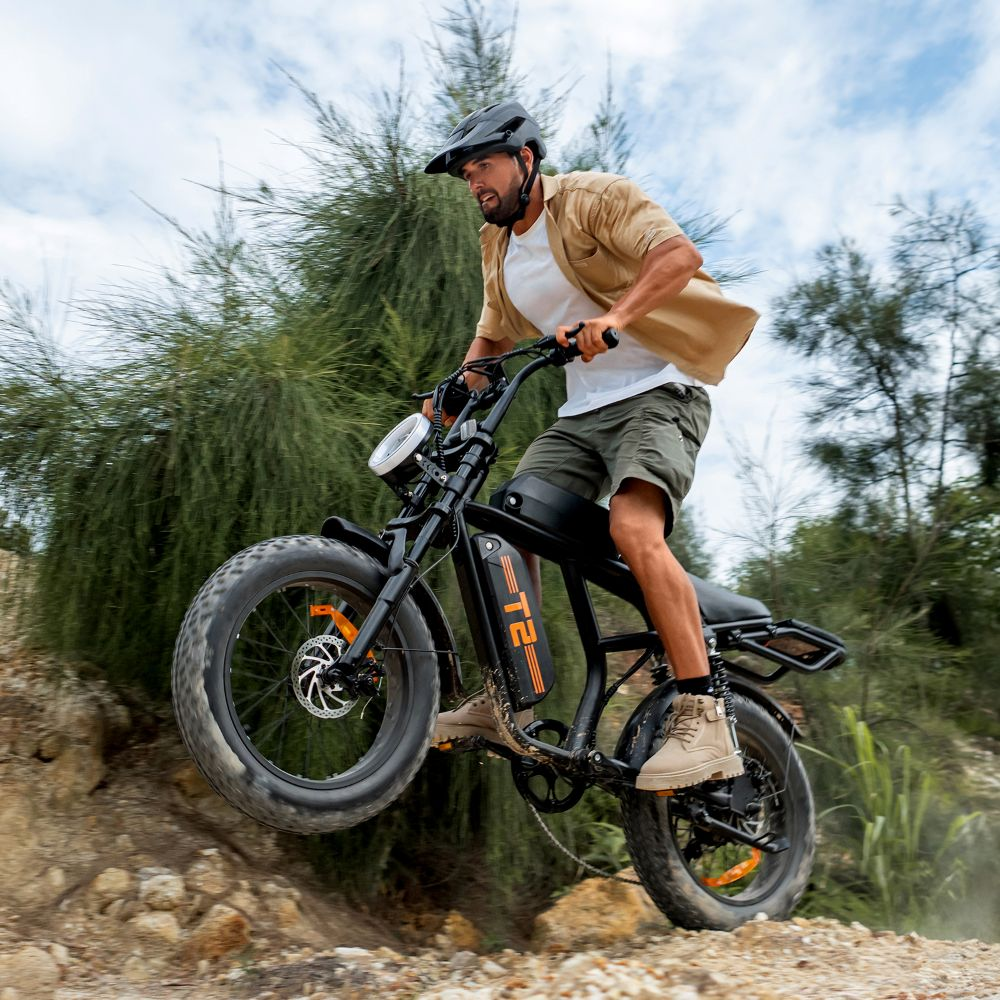 Un hombre monta una e-bike en terreno irregular, rueda delantera en el aire.
