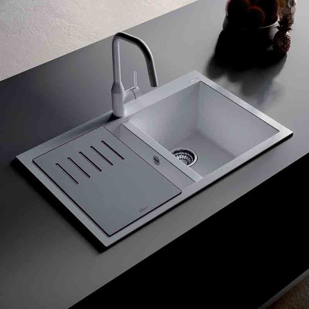 Un lavello da cucina grigio con rubinetto e scolo su un piano di lavoro scuro.