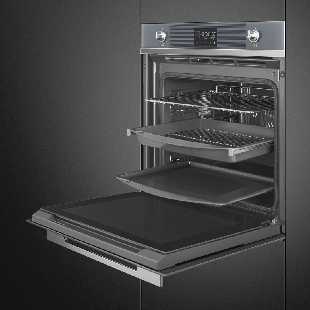 Un forno da incasso aperto con griglie e teglie estraibili su sfondo scuro.