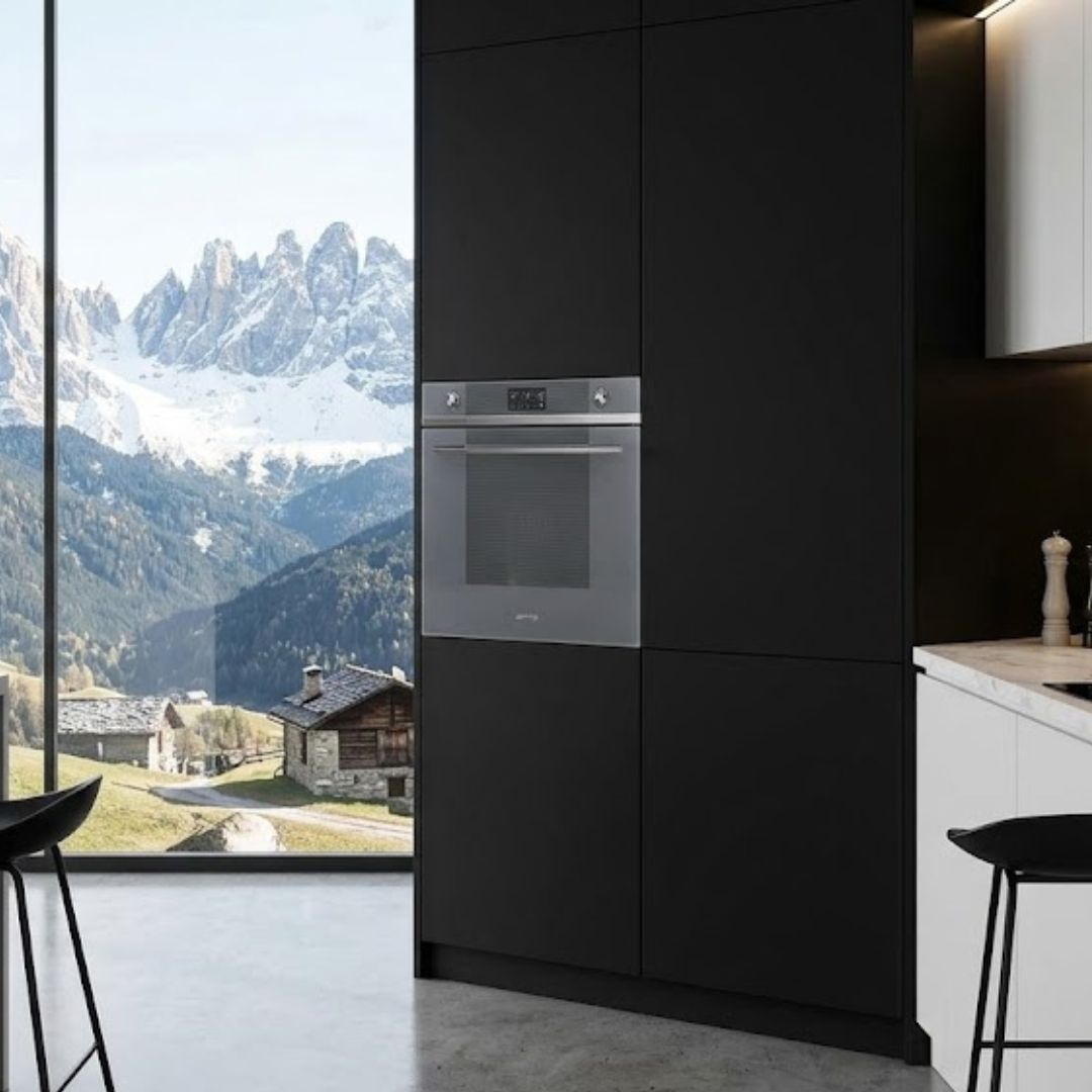 Moderna cucina nera con forno e vista sulle montagne innevate.