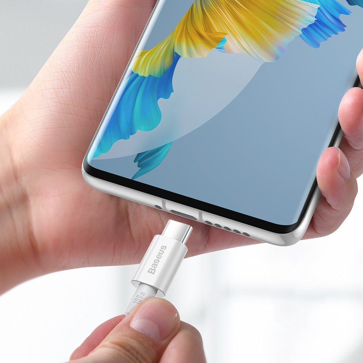 Eine Hand steckt ein weißes USB-C-Kabel in ein Smartphone.