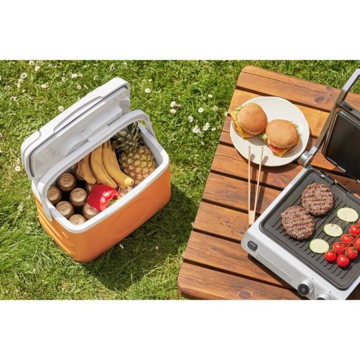 Kühlbox mit Obst und Getränken neben einem Grill mit Burgern und Gemüse.