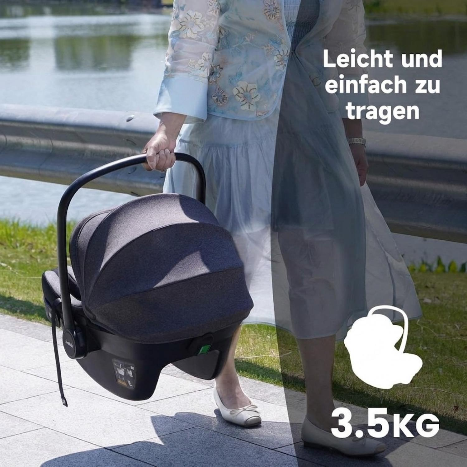 Eine Person trägt einen dunkelgrauen Kindersitz mit einem schwarzen Griff am See.