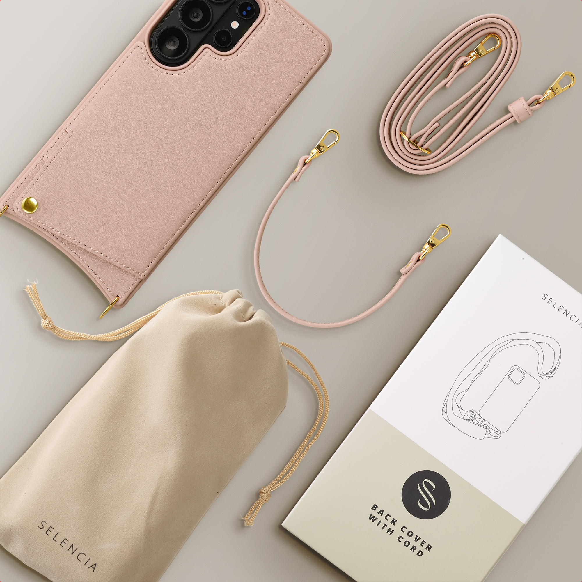 A pink phone case with cord, pouch, and packaging on a gray surface.