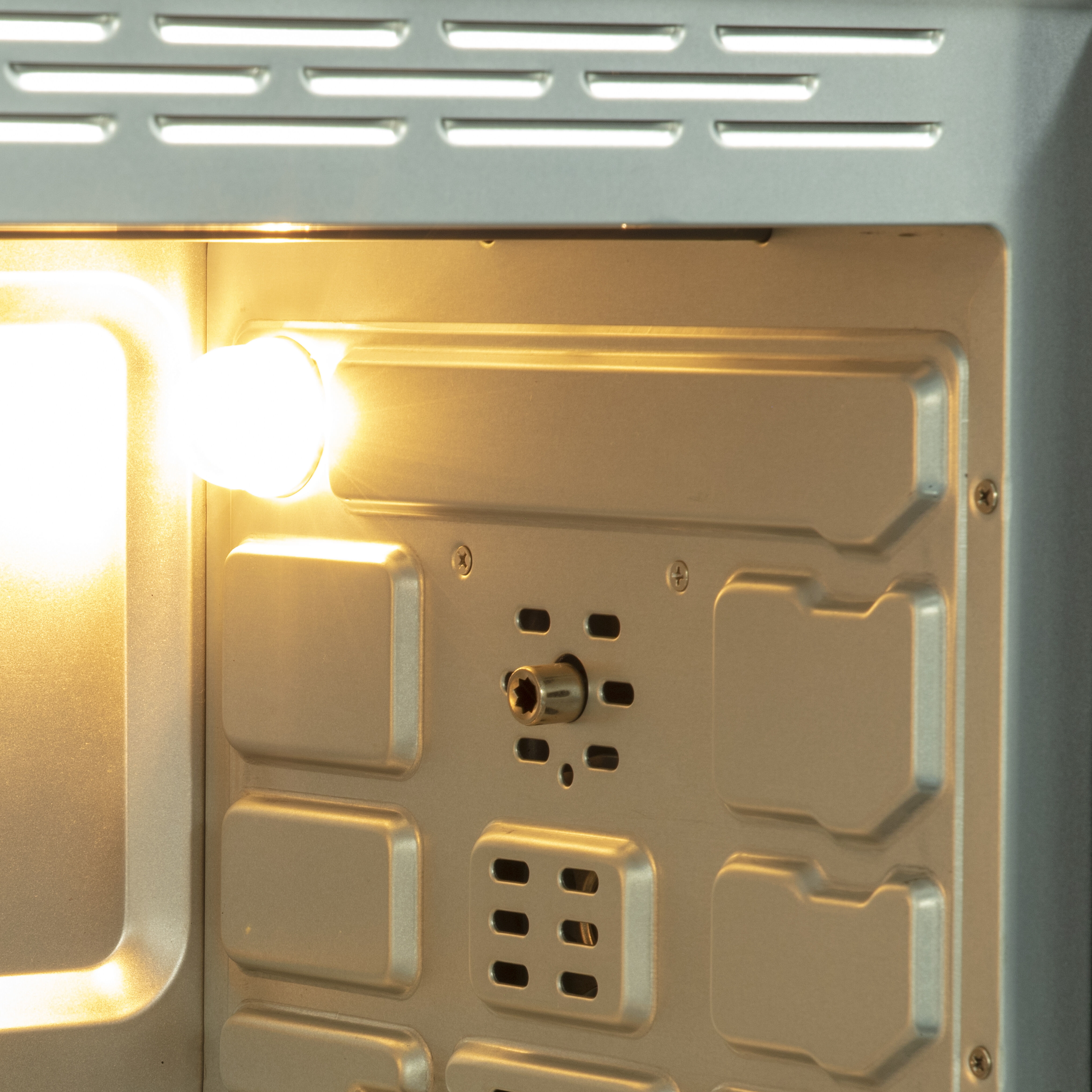 Inside of an oven with a lit heating element and ventilation slots.