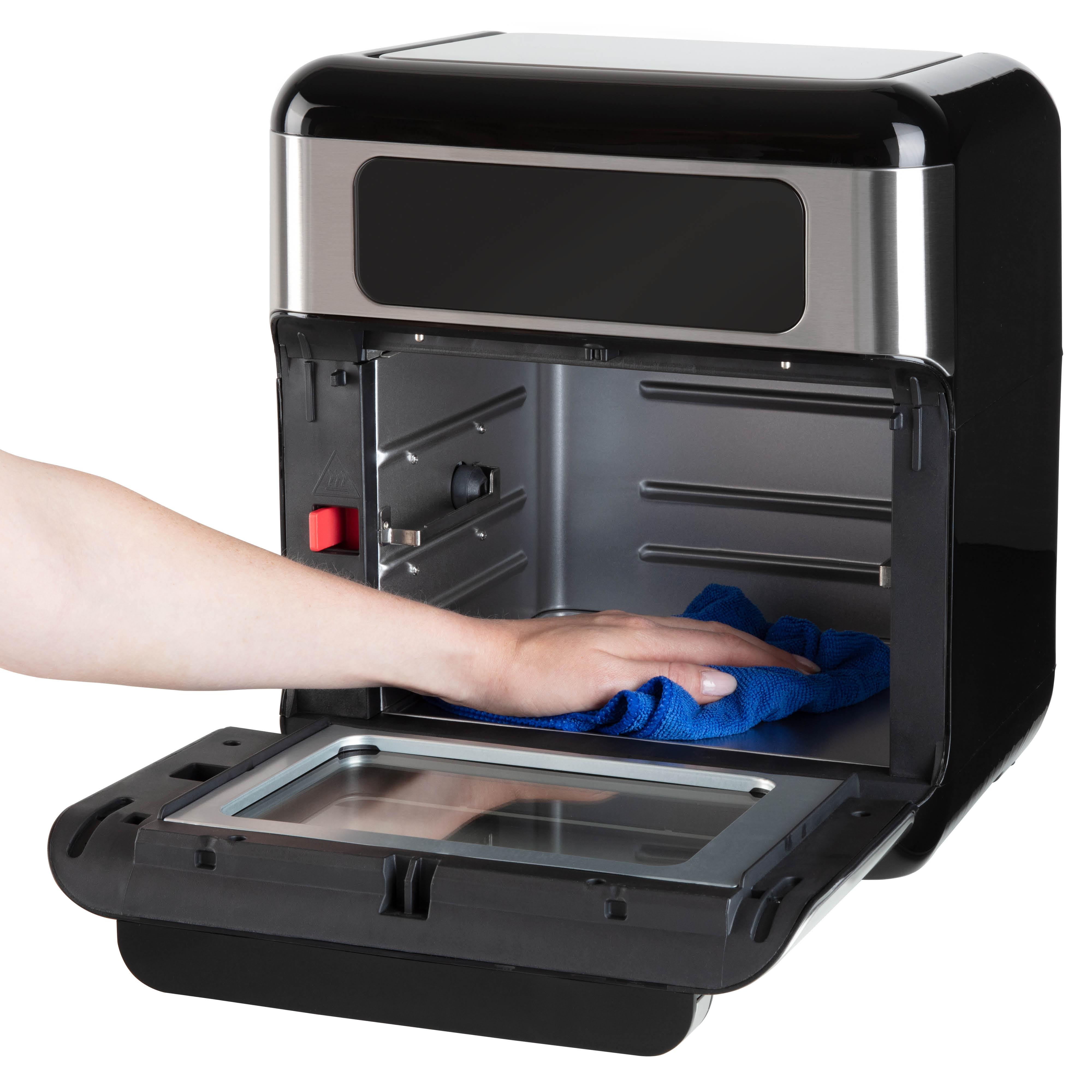 A hand cleans the inside of a black oven with a blue cloth.