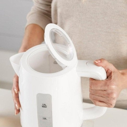 Una persona tiene un bollitore elettrico bianco con il coperchio aperto, mostrando l'interno.
