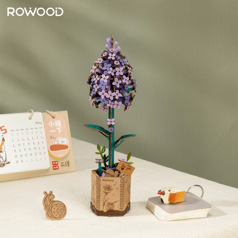 Un modèle en bois de fleur bleue dans un pot, à côté d'un calendrier et d'un escargot.