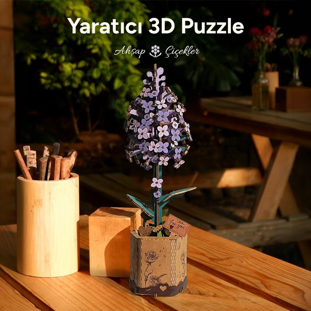 Un puzzle 3D en bois représentant une fleur violette en pot, à côté d'un gobelet en bois.