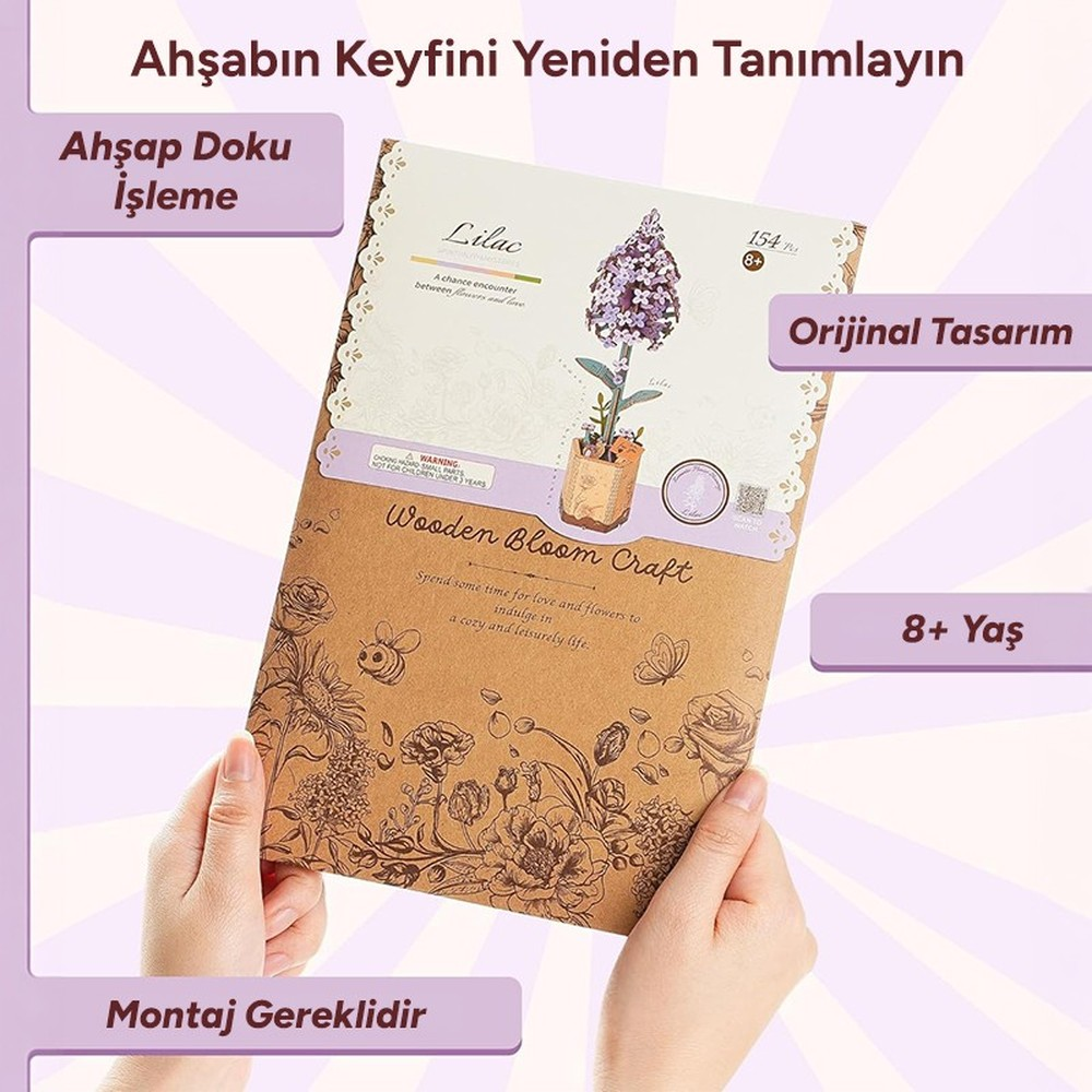 Des mains tiennent un kit d'artisanat de fleurs en bois avec des fleurs de lilas et des motifs floraux.