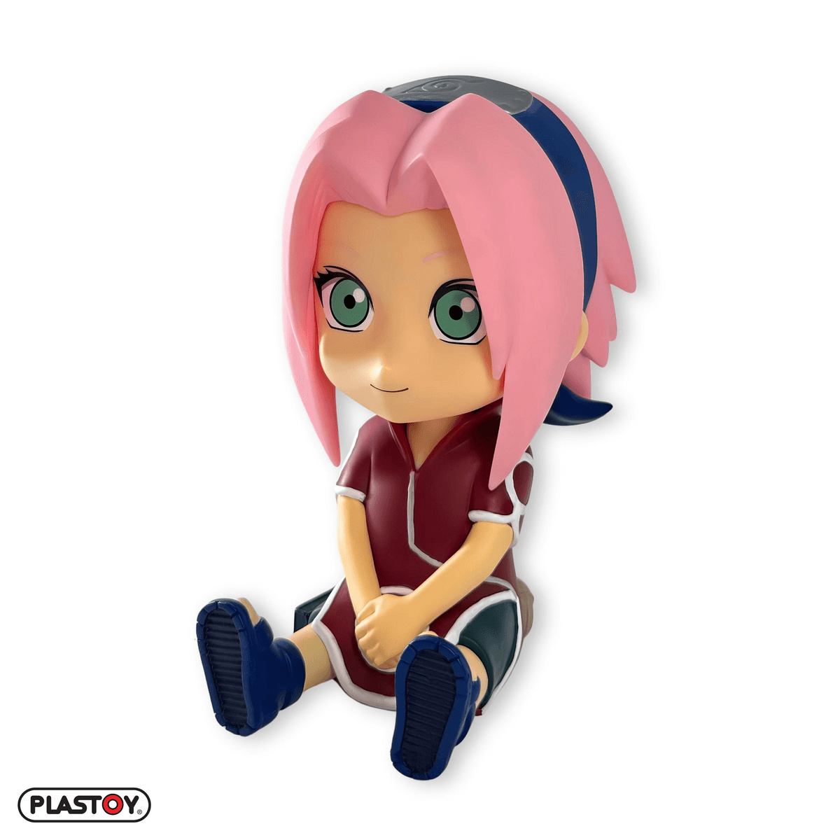 Una figura chibi de Sakura Haruno se sienta con las manos cruzadas delante. Viste un traje rojo.