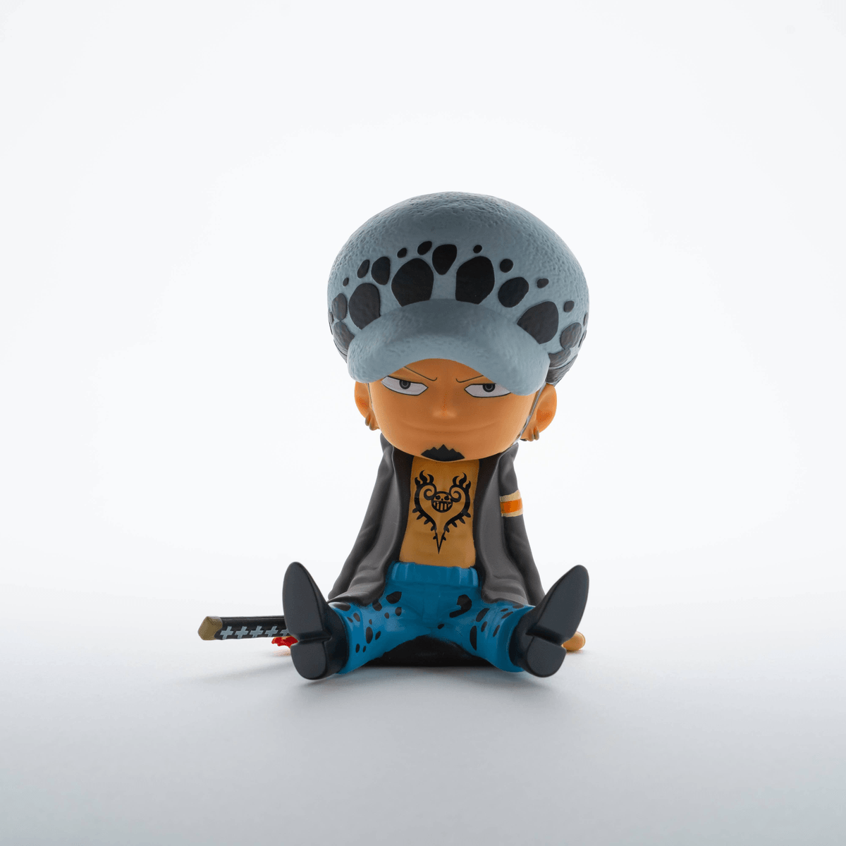 Una figura de Trafalgar Law sentado con espada, vistiendo su atuendo distintivo.