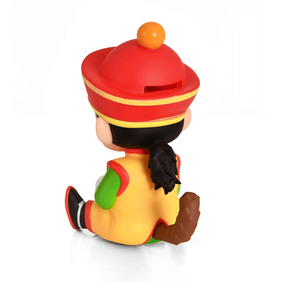 Eine kleine Figur mit rotem Hut, gelbem Overall und Affenschwanz sitzt.