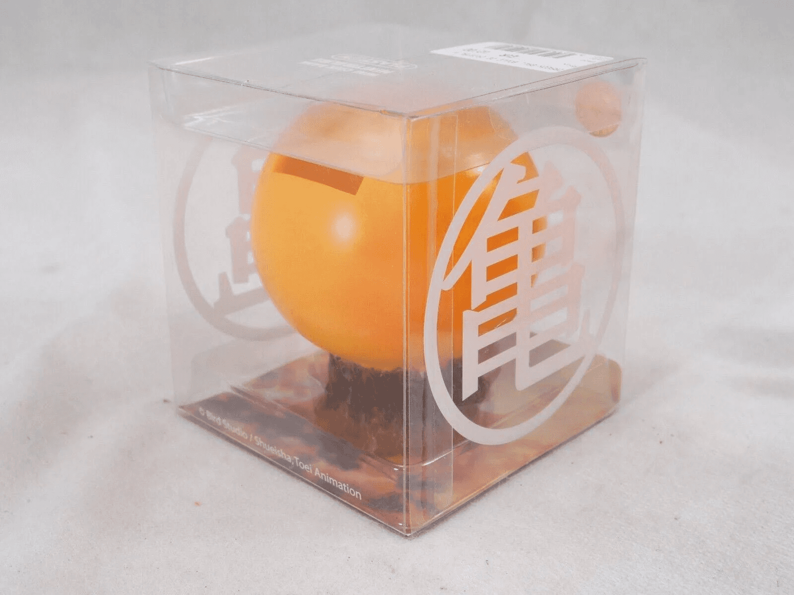 Ein orangefarbener Ball mit einer Schlitzöffnung, verpackt in einer durchsichtigen Box mit chinesischen Schriftzeichen.