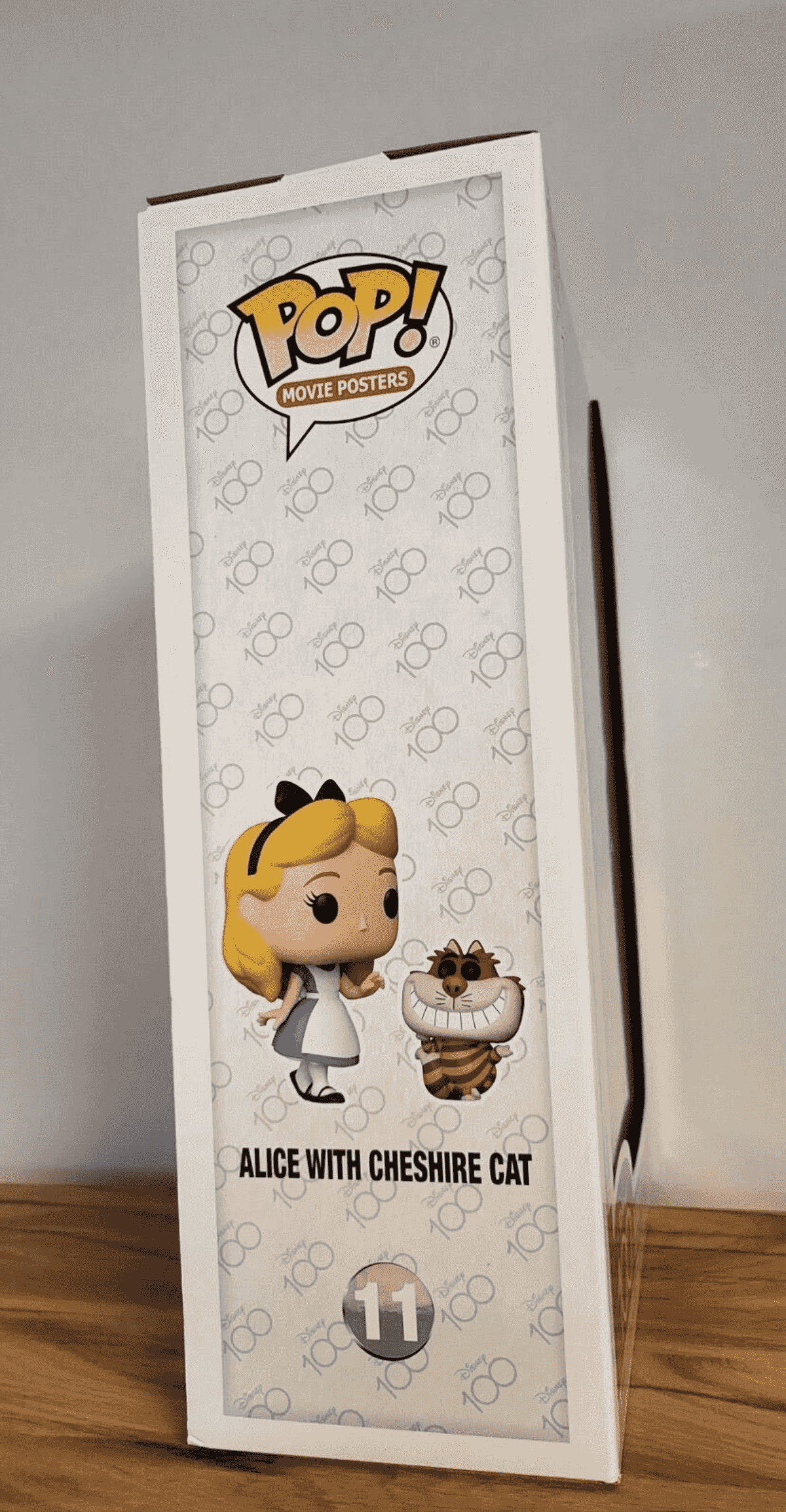 Scatola con figure di Alice e del Gatto Stregatto, logo Disney 100.