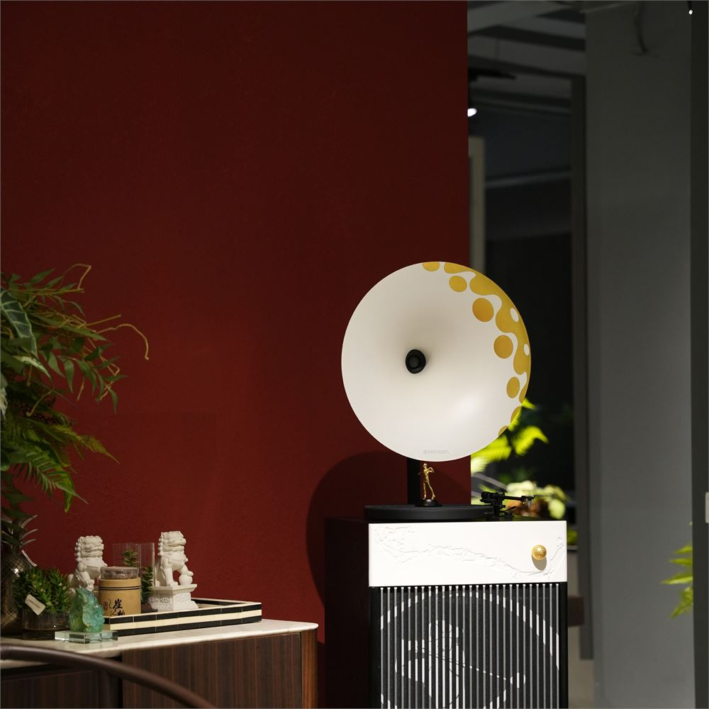 Sarı noktalı beyaz gramofon hunisi bir dolap üzerinde duruyor. Kırmızı duvar.