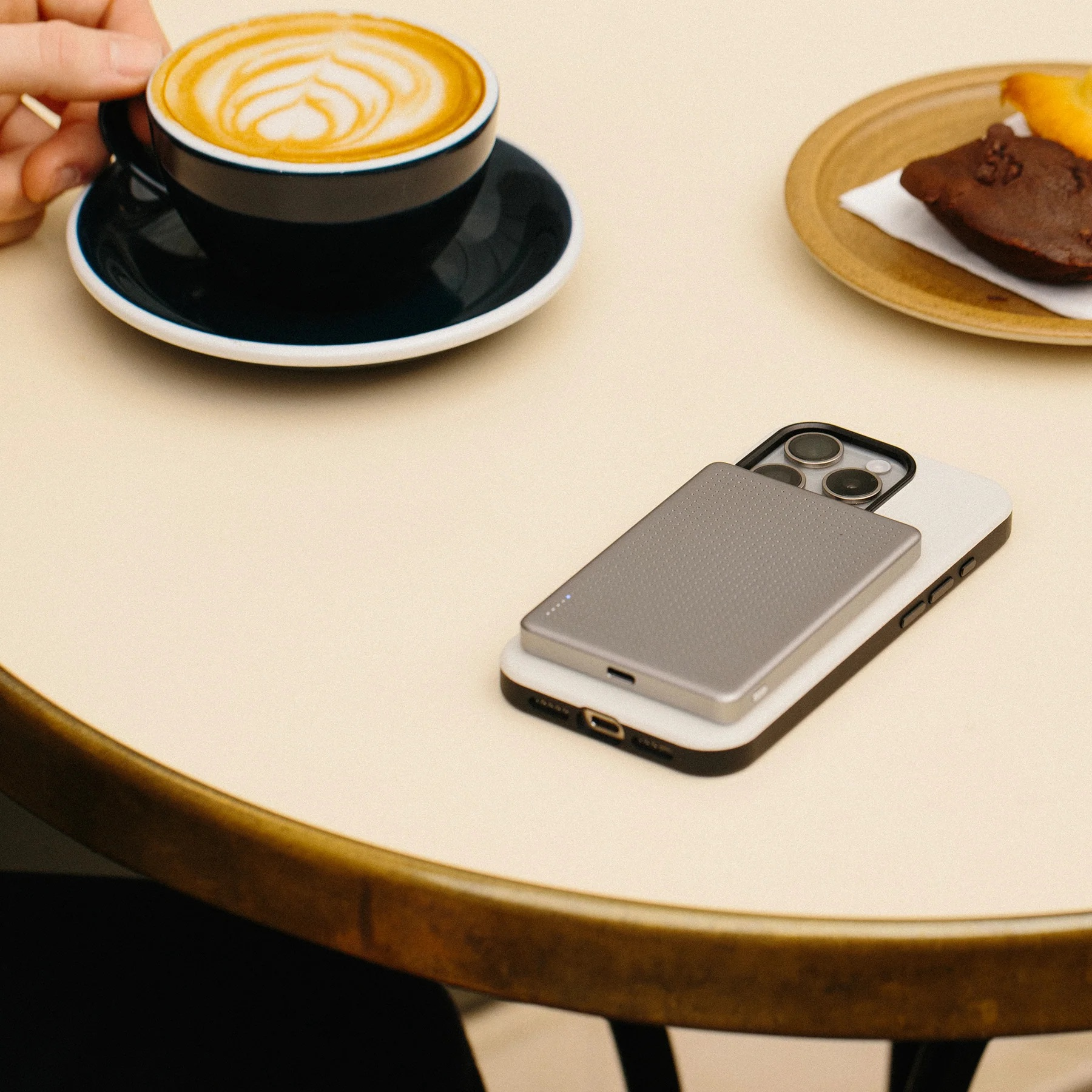 Une tasse de café avec art latte, un téléphone et une pâtisserie sur une table.