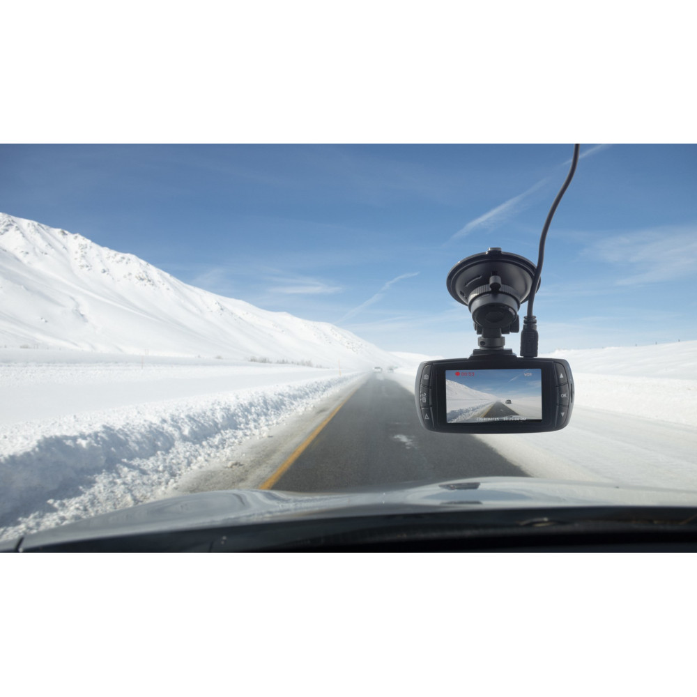 Eine Dashcam hängt an einer Windschutzscheibe, die eine verschneite Straße zeigt.
