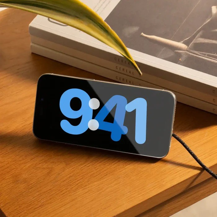 Un smartphone yace sobre una mesa de madera mostrando la hora 9:41.