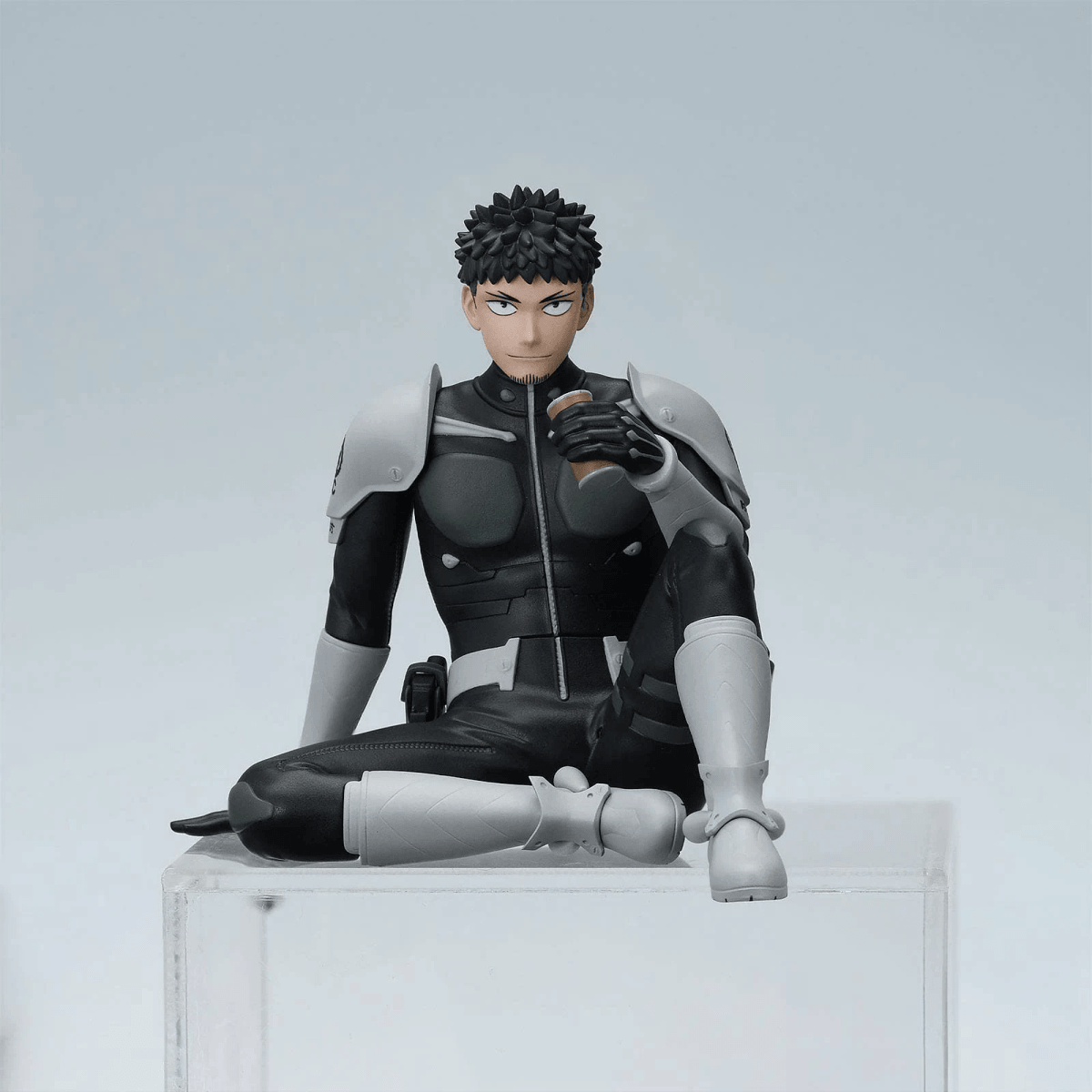 Una figura vestida de negro se sienta sosteniendo una taza marrón.