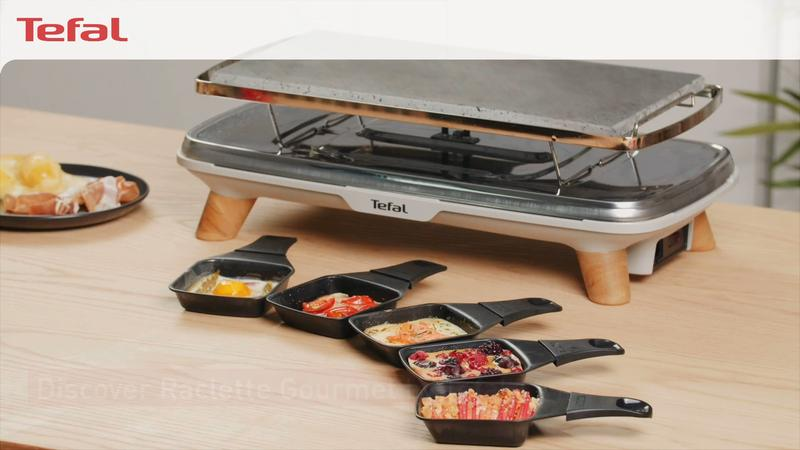 Ein Tefal Raclette-Grill mit Steinplatte und mehreren Pfännchen mit Essen.