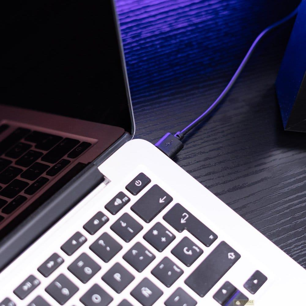 Ein USB-Kabel wird in einen Laptop gesteckt. Nahaufnahme der Tastatur.