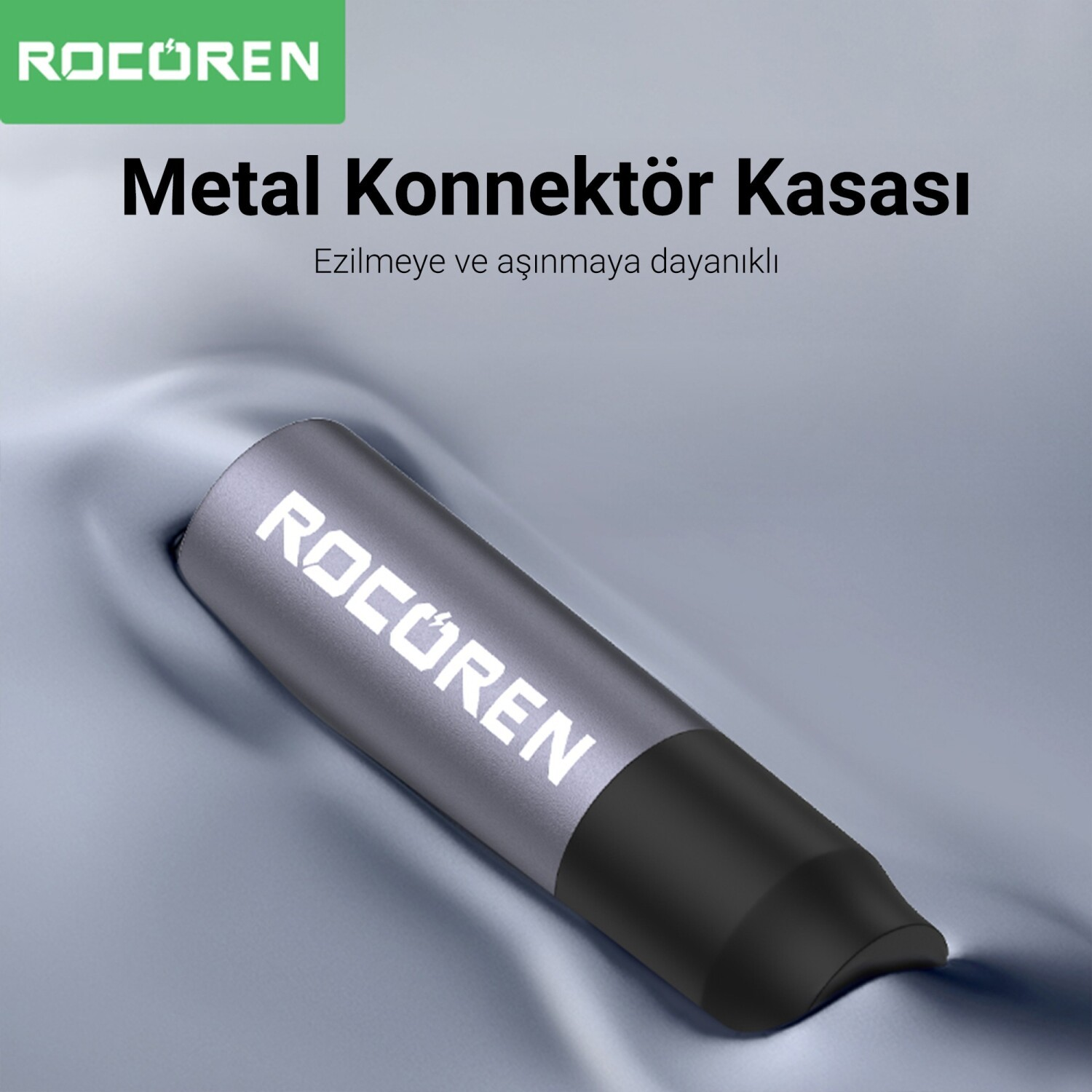 Gri kumaş üzerinde siyah kapaklı gri metal konnektör. Rocoren logosu.