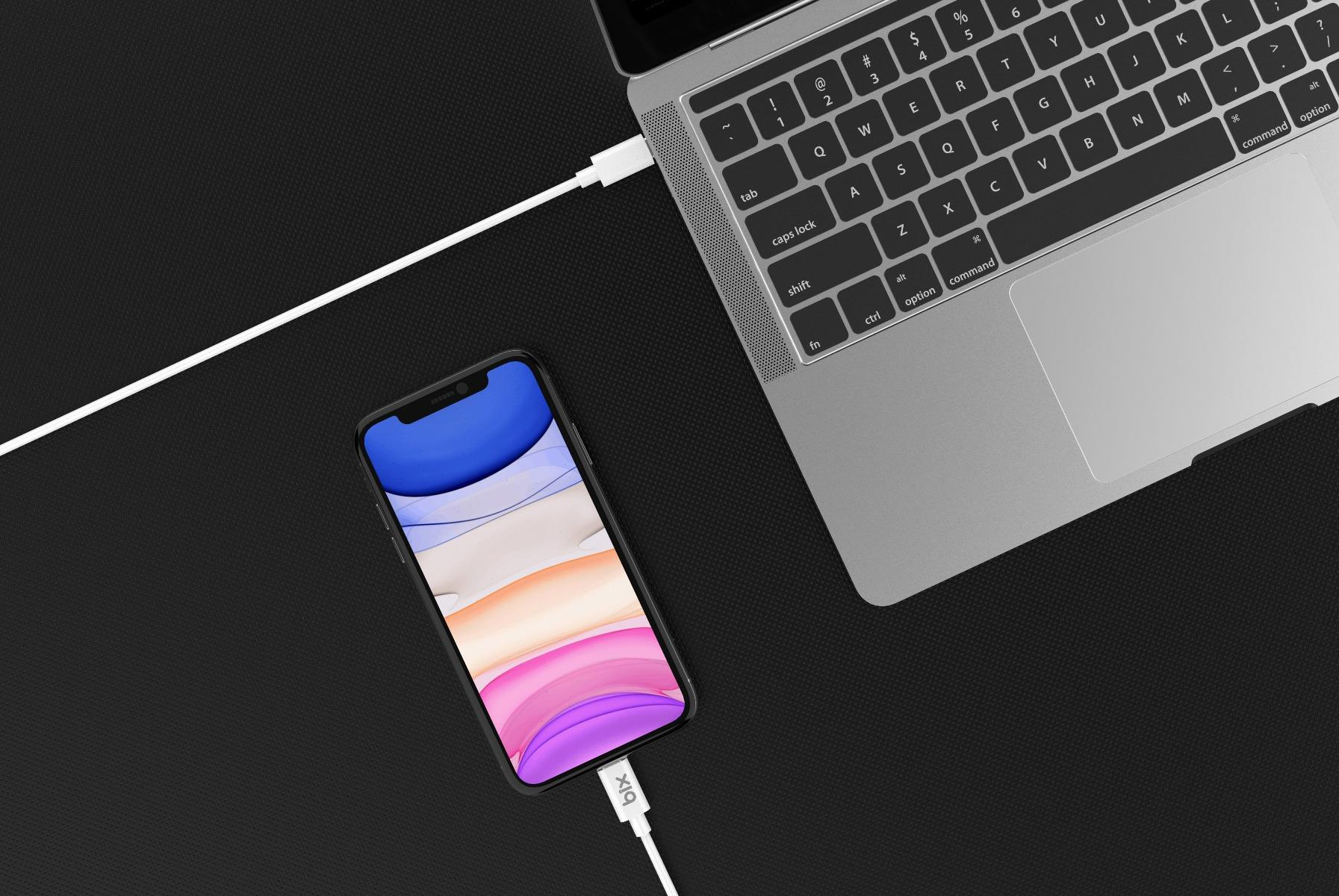 Bir iPhone, beyaz bir kabloyla dizüstü bilgisayara bağlıdır.