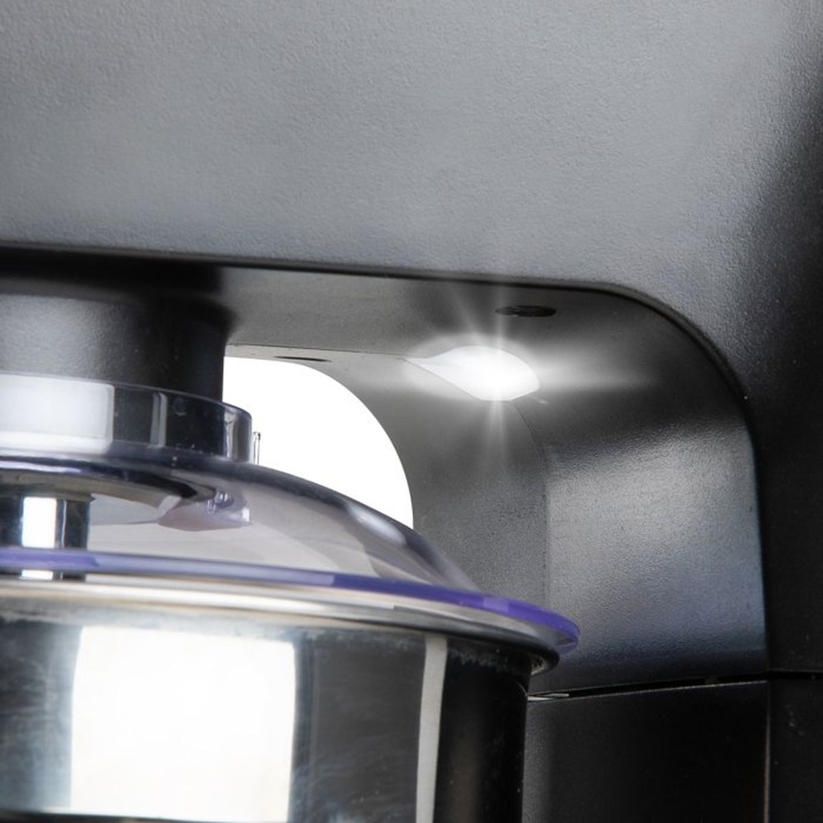 Primo piano di un elettrodomestico con cavità illuminata e ciotola in acciaio inox.