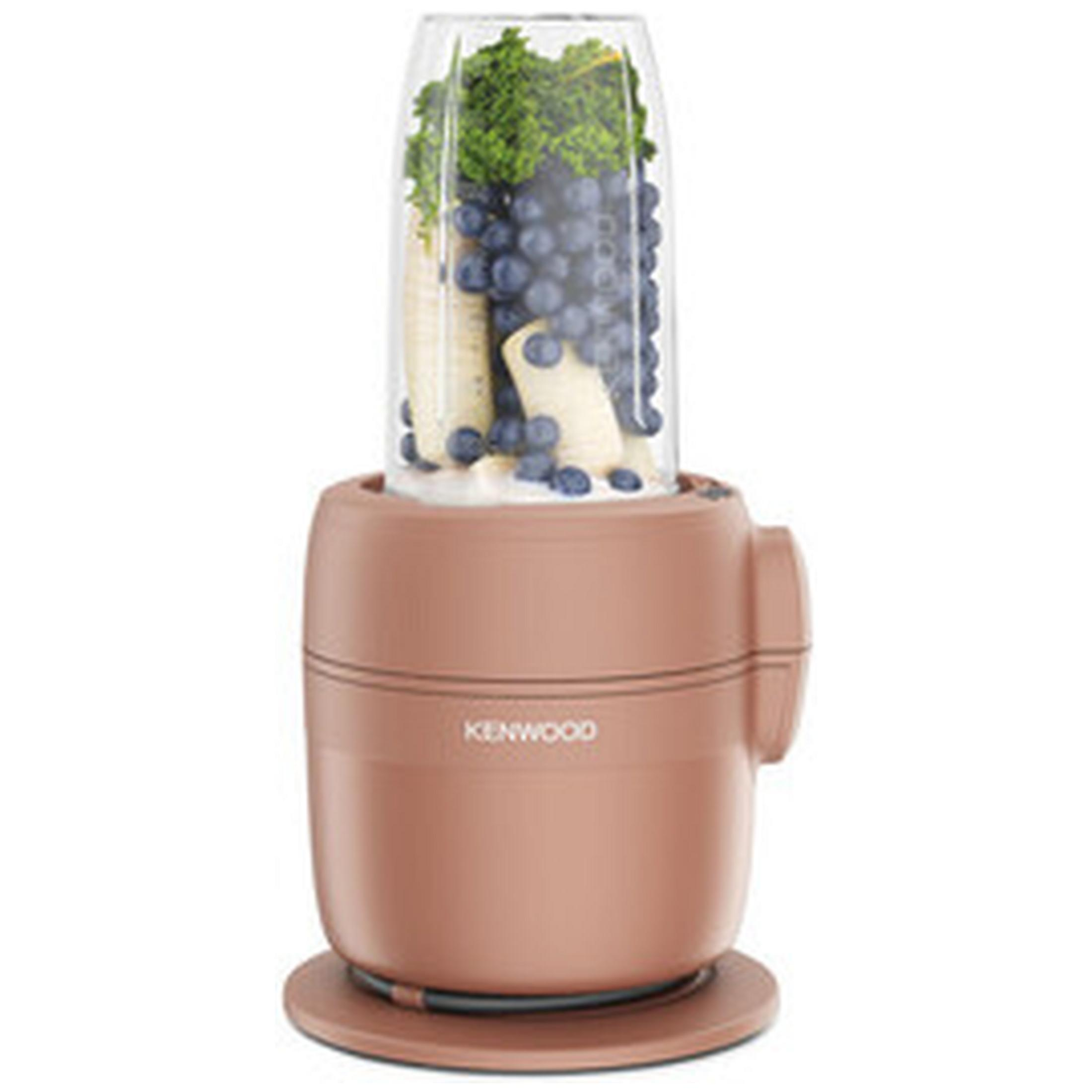 Un frullatore con bacche, banane e cavolo riccio nell'accessorio di vetro.