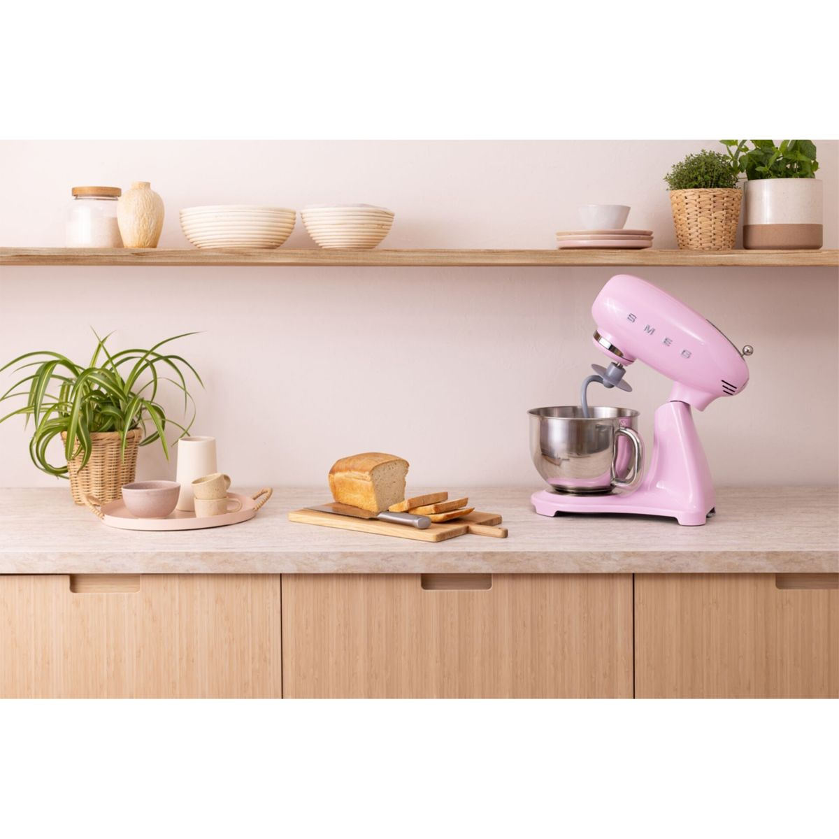 Un robot da cucina rosa è su un piano di lavoro accanto a una pagnotta e fette.