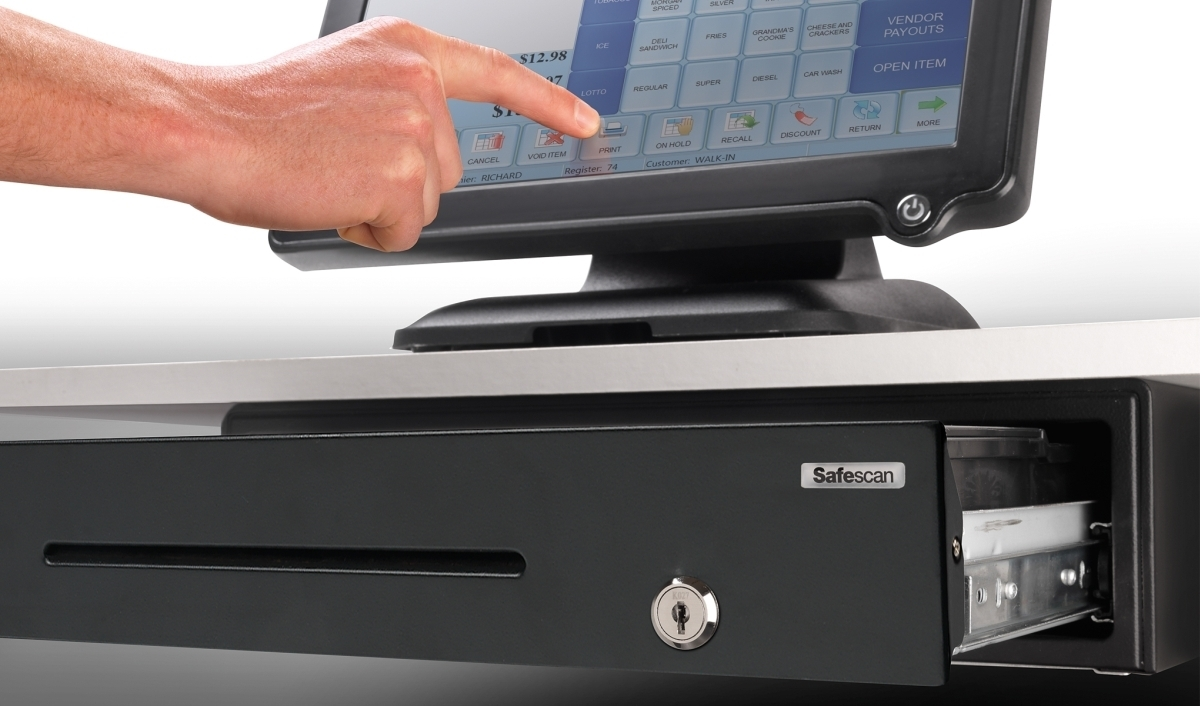 Ein Finger tippt auf dem Touchscreen eines Kassensystems. Eine Schublade ist offen.