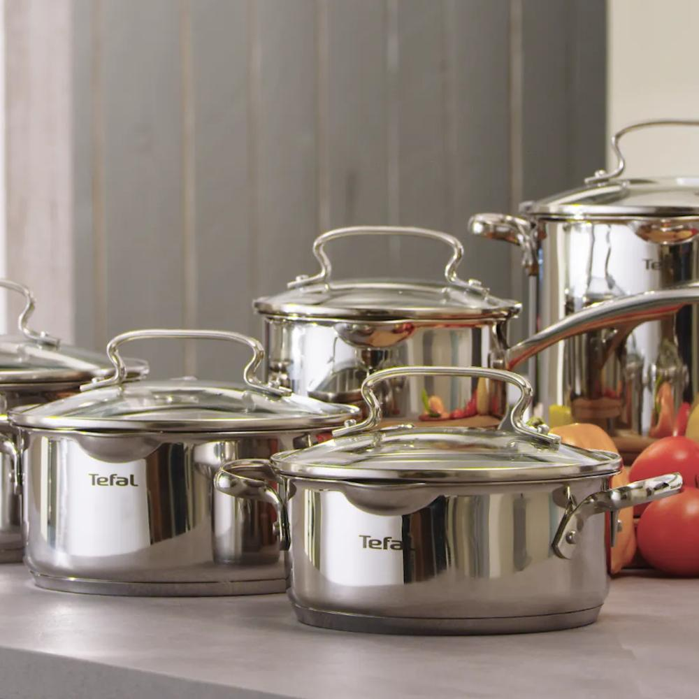 Meerdere glanzende Tefal kookgerei sets met glazen deksels staan op een aanrecht.