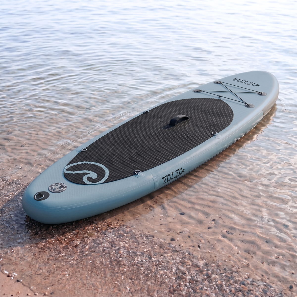 Ein hellblaues aufblasbares Stand-Up-Paddleboard liegt halb im Wasser am Strand.