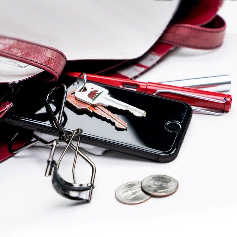 Chiavi, telefono, arricciaciglia e monete dentro una borsa.